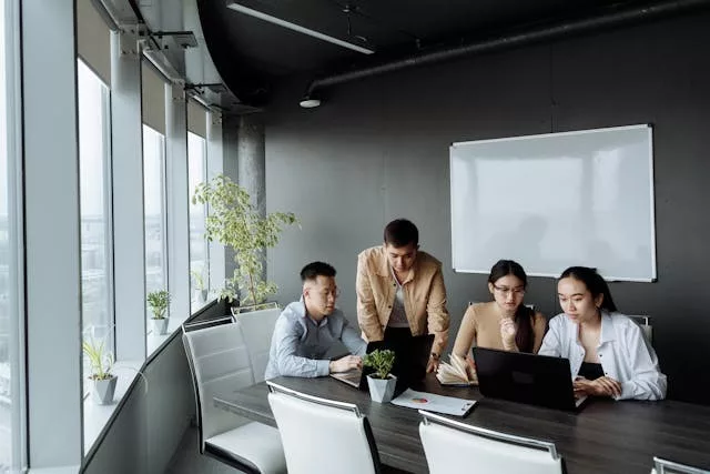 Grupo de seis personas en una sala de reuniones moderna observando una pantalla interactiva durante una presentación colaborativa sobre inteligencia artificial en el trabajo, con ordenadores